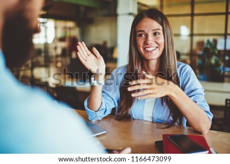 Happy successful hipster girl explaining information to male friend sitting in front, positive man and woman talking and discussing ideas for new startup project at spending time in coworking space Stock foto © 