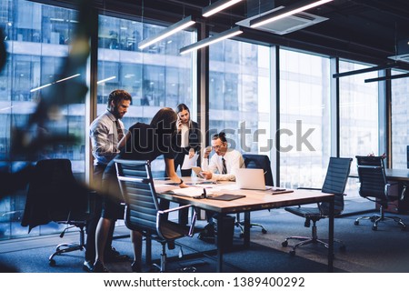 Cooperation process of professional male and female colleagues,business woman in formal suit communicate with operator via smartphone gadget while reading email from partners touch pad during teamwork Foto d'archivio © 