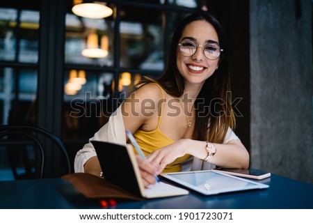 Portrait of sincerely woman in spectacles using 4g wireless internet connection on modern touch pad during leisure in city, prosperous millennial blogger with digital tablet smiling at camera Imagine de stoc © 