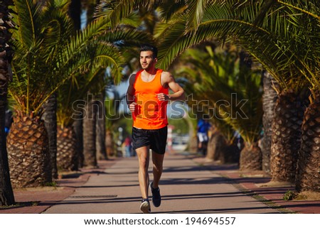 Attractive strong athlete jogging at evening