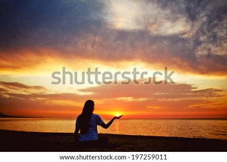 Silhouette of a beautiful woman holding the sun in hand, paradise dawn