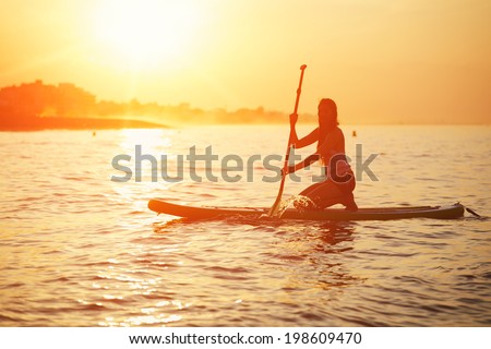 Silhouette of paddle surf yoga at the amazing sunset over the sea, spiritual yoga meditation on the beach