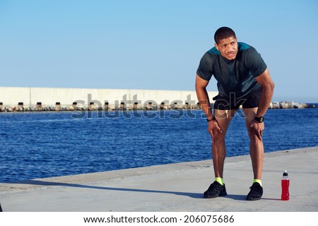Motivation to run, exhausted african american runner resting tired after evening training outdoors, athletic jogger with muscular body taking break in sea port, fitness and healthy lifestyle concept