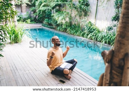 Emotional man freelancer raising hands celebrate achievement of successful online project and approved deal, overjoyed male with laptop computer feeling accomplished with digital nomad at pool terrace Stock foto © 