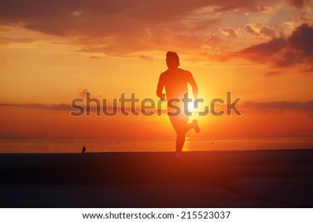 Male runner with muscular body running alone at orange sunrise on the beach, fitness training on the beach, beautiful runner silhouette in action, fitness and healthy lifestyle concept