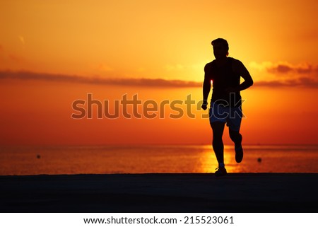 Male runner with muscular body running alone at orange sunrise on the beach, fitness training on the beach, beautiful runner silhouette in action, fitness and healthy lifestyle