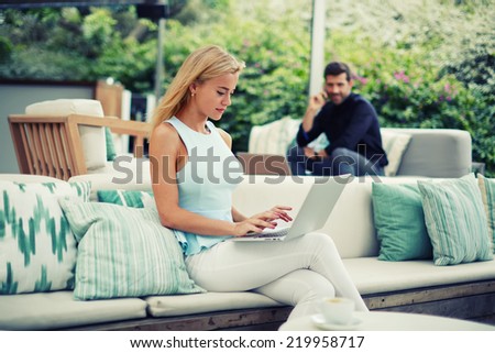 Businesspeople using technology, attractive blonde hair woman typing something on computer keyboard sitting on the terrace of modern lounge bar cafe,success businessman having cell mobile conversation