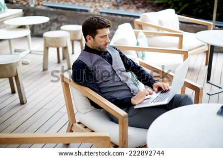 Handsome hipster man working with his laptop on the beautiful restaurant, work everywhere