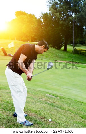Professional golf player in action hitting golf ball at beautiful sunny evening, holidays leisure of wealthy man