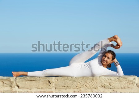 Attractive girl meditating and exercising in yoga pose on high altitude with amazing view on background, healthy woman smiling during yoga training outdoors, woman practicing yoga enjoying sunny day