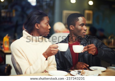 Two young friends holding cups drink coffee in cafe, friends enjoying coffee in beautiful place, cold winter days in beautiful coffee shop, friends at breakfast having coffee and enjoying themselves