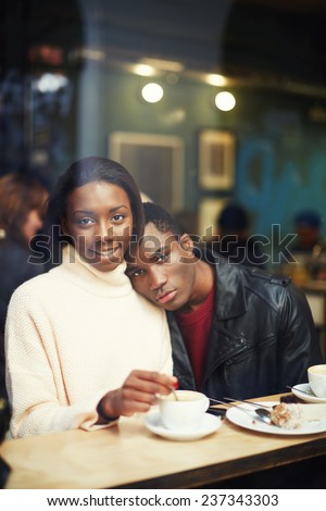 Charming young woman sitting in cafe with her gay friend, friends at breakfast having coffee and enjoying themselves, two people in cafe enjoying the time spending with each other, view through window