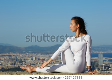 Beautiful healthy woman meditating yoga and enjoying sunny evening, beautiful girl seated in yoga pose on amazing city background