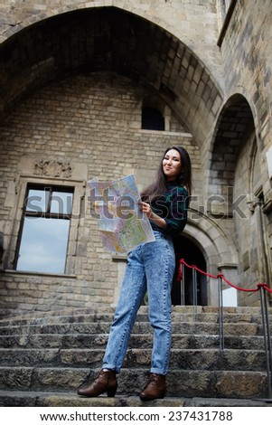 Young female traveler searching right direction on city map, beautiful tourist woman on vacation with a map in antique gothic city,pretty young female tourist studying a map standing in gothic quarter
