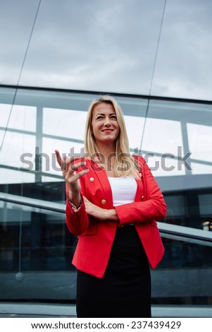 Portrait of smiling confident businesswoman, happy businesswoman or manager standing against skyscraper office building, wealthy and elegant successful woman, portrait charming woman with great smile