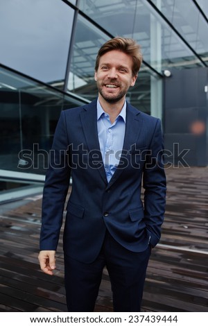 Portrait of smiling confident businessman, happy businessman or manager standing against skyscraper office building, wealthy successful man in suit smiling, portrait handsome man with great smile
