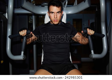 Half length portrait of young bodybuilder working out with chest muscles on press machine