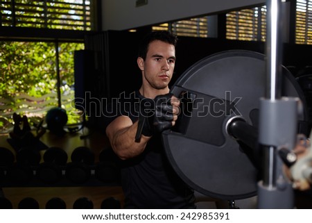 Young athletic man preparing barbell for working out at health fitness center, young bodybuilder change barbell weights for fitness training at gym