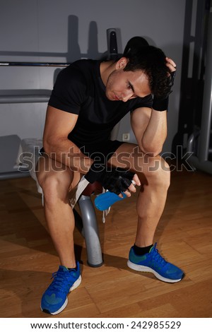 Young athletic man having a rest after working out at gym, athletic sportsman lower his head tired to struggle and fight with himself