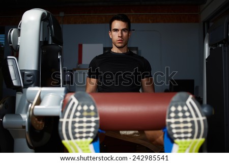 Handsome young athlete doing legs press at gym, attractive fit man working out with quadriceps muscles on press machine