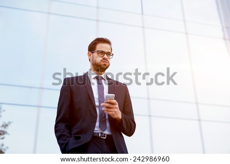 Handsome businessman receiving shocking news as he reads a text message on mobile phone