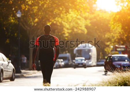 African-american fit man walking at sunrise while resting after run