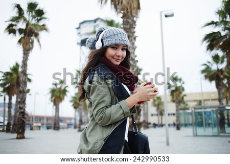 A young woman listening to music on her headphones walking outdoors