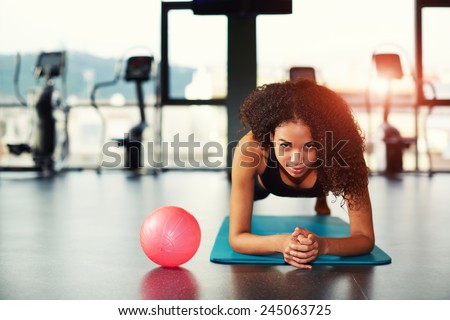 Attractive young woman leaning on her elbows doing exercise for buttocks muscles at gym