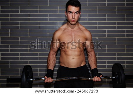 Portrait of handsome weightlifter lifting barbell exercising chest and biceps muscle at gym