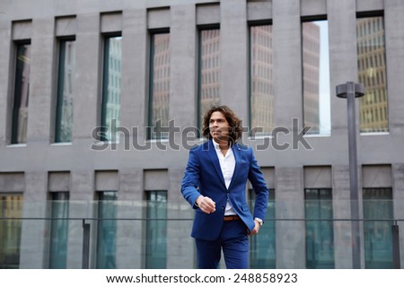 Shot of a handsome businessman in a suit walking through the city looking confident