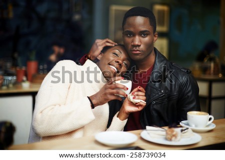 Portrait of young couple in love having fun drinking coffee in cafe, romantic dark skinned couple sitting in coffee shop enjoying the time spending with each other