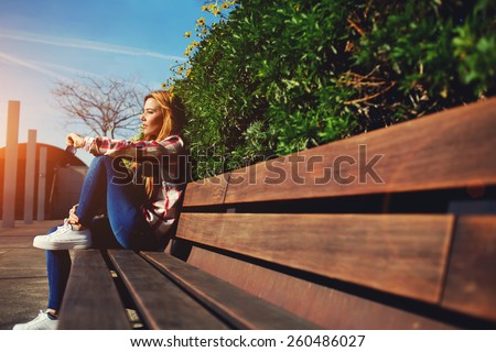 Side view seated woman on the bench enjoying nature in sunny day outdoors, charming young girl relaxing in the spring park, female student relaxing at campus, flare sun light