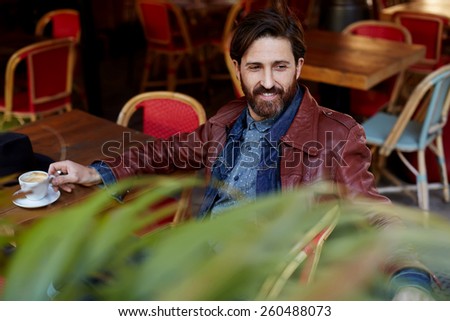Portrait of handsome aged hipster man sitting in a restaurant terrace enjoying a good day, stylish man looking so satisfied and happy while sitting outdoors