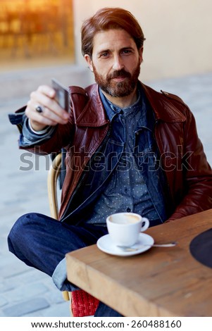 Portrait of handsome hipster man paying for his coffee with a credit card at the cafe, customer paying at a coffee shop with a credit card, flare sun light