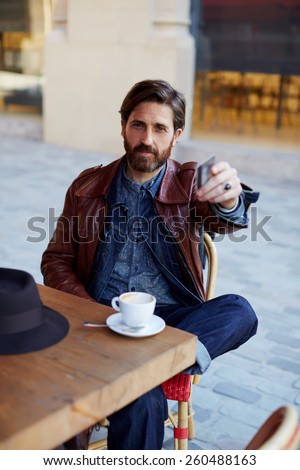 Portrait of handsome hipster man paying for his coffee with a credit card at the cafe, customer paying at a coffee shop with a credit card