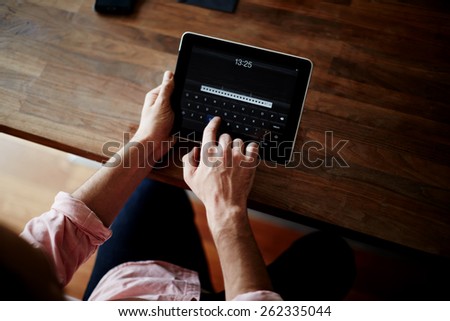 Cropped shot of a man\'s hands using a digital tablet at cowering office, on-line shopping at home, cross process, filtered image, data security
