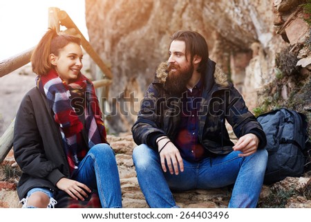 Couple of backpackers resting while out hiking in mountains, couple of hipster guys smiling while having conversation, adventure trip in mountains, hike tour in mountain landscape, flare sun