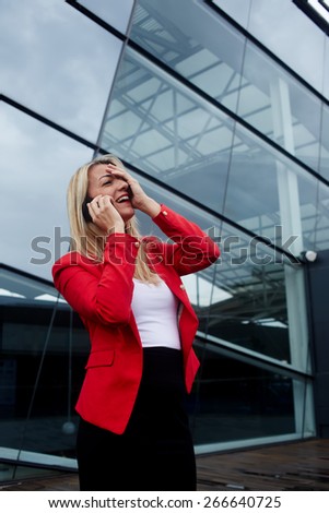 Portrait of attractive businesswoman throwing her head back with one hand on her face in laughter having conversation on cell phone, woman laughing during talking to friend on smart phone