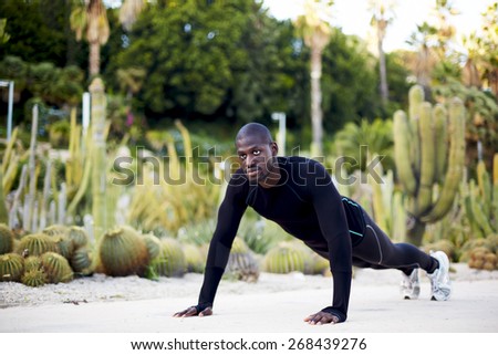 Fit man working out in the park doing push-ups exercise, sporty black man training outdoors