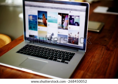 Workplace with open laptop with black screen on modern wooden desk, angled notebook on table in home interior, filtered image, cross process