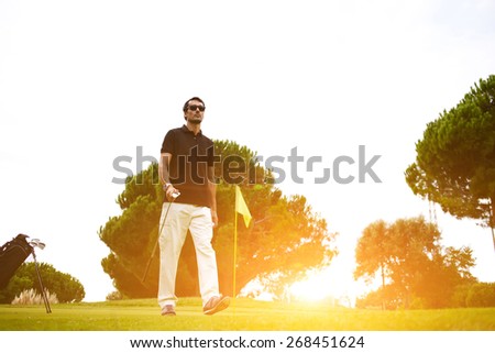 Full length portrait of professional golf player walking to the next hole on beautiful course, good golf game at sunny summer day on the course, bright flare sunset light