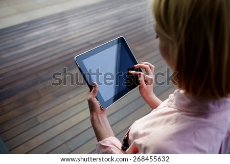Close up young blonde female student using touch pad against wooden background, freelancer girl working on her digital tablet with big copy space,hipster woman browsing with touchscreen device, filter