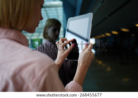 Rear view female person using digital tablet, business woman or freelancer working on touch pad in elevator, businesswoman using her wireless devices in modern office, young successful browsing on pad