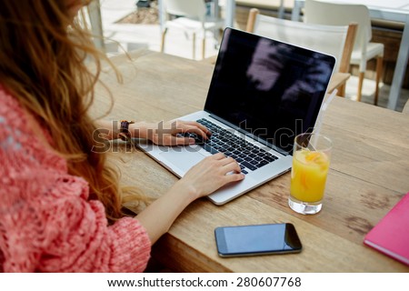 Creative female freelancer sitting front laptop computer with blank copy space screen for your information, young business woman work on notebook typing text during breakfast in modern coffee shop