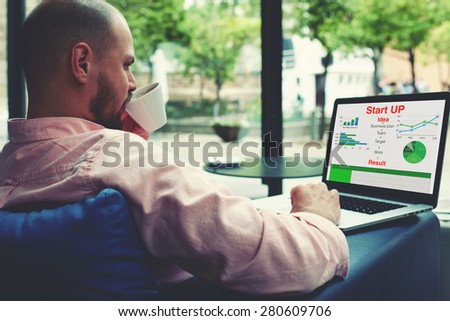 Experienced businessman sitting front laptop computer with financial information as graphics and charts,young entrepreneur work on notebook drinking coffee while sitting in modern hotel interior