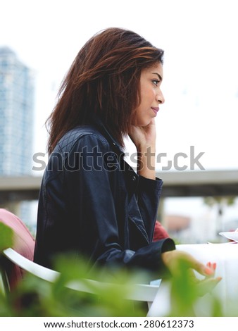 Attractive afro american woman talking on the smart phone while sitting at coffee shop terrace, young female having cell phone conversation sitting at restaurant table during her recreation weekend
