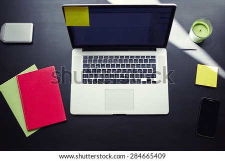 Top view of workplace with open laptop computer, colorful notebooks and stickers, modern table at window in home interior, distance work or on-line learning concept, freelancer needs workstation