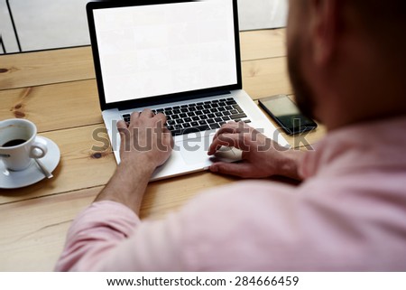 Back view of male person sitting front open laptop computer with blank empty screen for your information or content, modern businessman working in internet via notebook,student at coffee shop learning