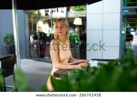 Portrait of attractive caucasian woman enjoying a good day at modern terrace of coffee shop, charming female hipster waiting someone at sidewalk cafe with green plants, businesswoman at coffee break