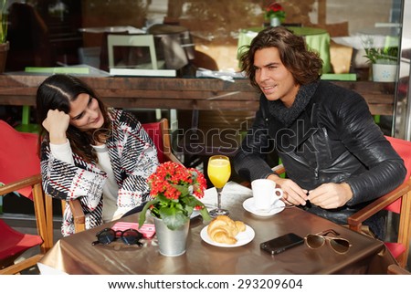 Charming young woman sitting in sidewalk cafe and breakfast with her best friend,two people enjoying and spending time together at pleasant conversation,couple of tourists taking break after city walk